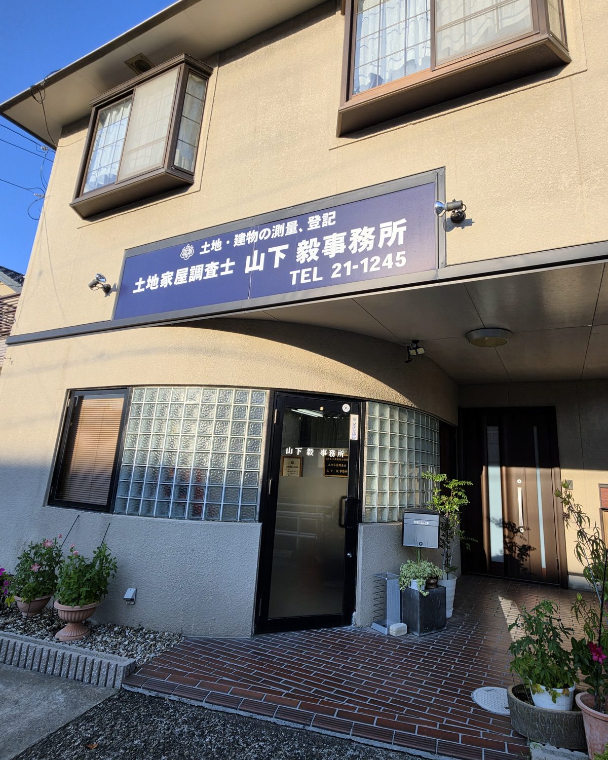 山下土地家屋調査士事務所の外観。「土地・建物の測量、登記 土地家屋調査士 山下毅事務所」の看板が掲げられています。